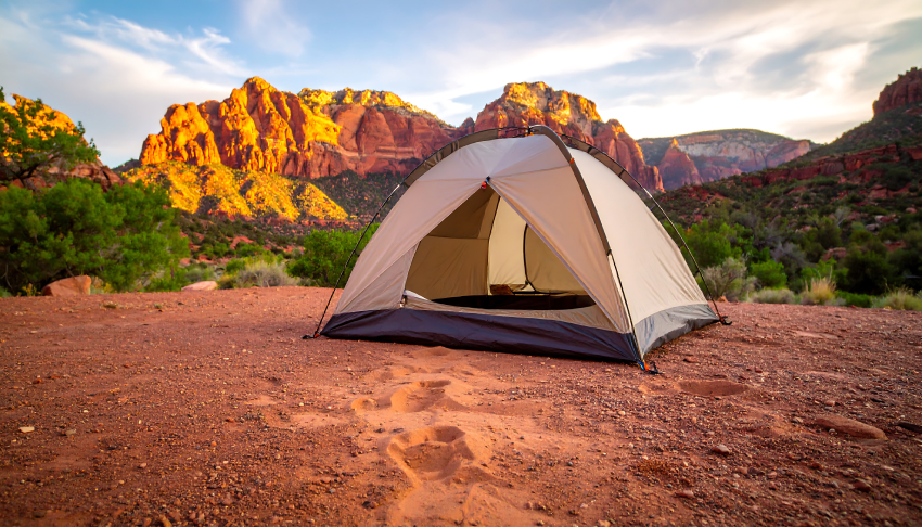 Camping Tent in Desert Landscape at Sunset with Red Rock Formations