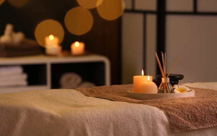 Burning candles and aromatic reed freshener on table in spa salon, space for text